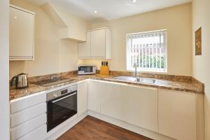 a kitchen with white cabinets and a sink and a window at Host & Stay - The Moorings in Runswick