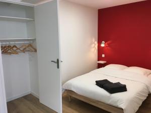 a bedroom with a white bed with a red wall at STUDIO DU MARCHÉ in La Rochelle