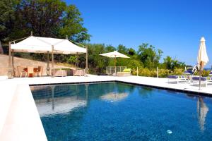 uma piscina com água azul e guarda-sóis em Villa Francesca Relais em Gradara