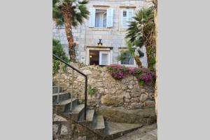 a stone house with palm trees and stairs in front at Studio Apartment Marella in Vis
