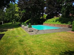 a swimming pool with chairs in a yard at De Eppenbeek in Swalmen