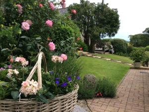 a basket of flowers in a garden with a lawn at Frogwell in Strete