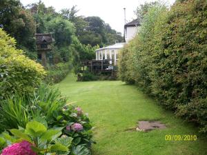 a garden with a house and some bushes and flowers at Frogwell in Strete