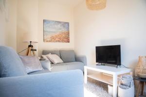 a living room with a couch and a tv at Heart at Sea - De Haan in De Haan