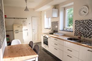 a kitchen with white cabinets and a table and a sink at Heart at Sea - De Haan in De Haan