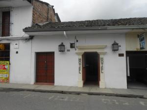 a white building with two doors on a street at Hotel Alcayata Popayan in Popayan
