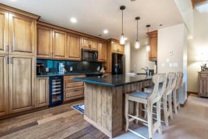 a kitchen with wooden cabinets and a large island with bar stools at 326 Kiva Condo access to Ski in Out in Avon