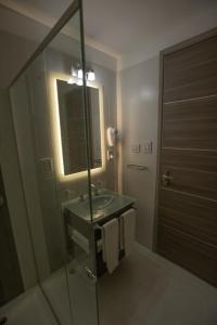 ein Bad mit einem Waschbecken, einem Spiegel und einer Dusche in der Unterkunft ÑU Posta Urbana Hotel Boutique in Cordoba