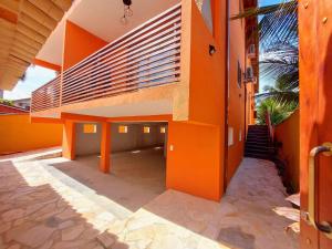Un edificio naranja con un banco al costado. en Mamanguá - Apto c/ piscina, 50mts da praia, cozinha, churrasqueira, ar con, WiFi, netflix, garagem, en Paraty