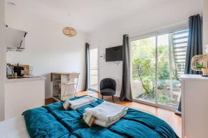 - une chambre avec un lit bleu et une grande fenêtre dans l'établissement Studio au calme au Bouscat - le Gambetta, à Le Bouscat