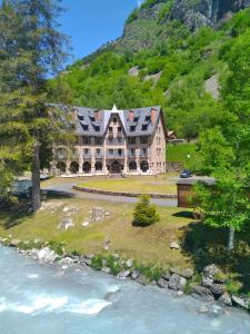a large house on a hill next to a river at Hôtel Vignemale in Gavarnie