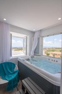 eine große Badewanne in einem Zimmer mit einem großen Fenster in der Unterkunft Divine Naxos Villa in Plaka