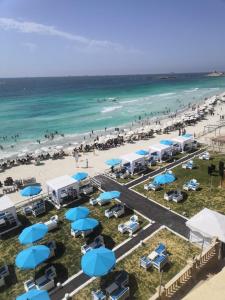 uma vista aérea de uma praia com guarda-sóis azuis e brancos em Agami Apartment em Alexandria