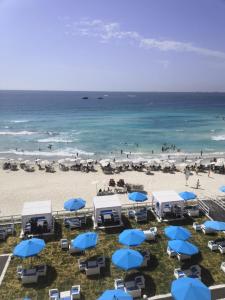 plaża z niebiesko-białymi parasolami i oceanem w obiekcie Agami Apartment w Aleksandrii