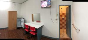 a room with a table and red chairs and a tv at Baan Suan BBQ and Resort ชั้น2ห้อง9สองเตียง in Khon Kaen