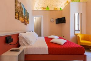 een slaapkamer met een rood-wit bed en een gele stoel bij Terrae Rooms Rental in Mesagne