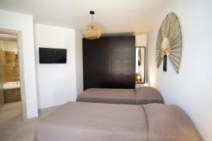 een slaapkamer met 2 bedden, een tv en een bank bij Les Villas de la Résidence U Veniqui in Favone