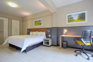 um quarto com uma cama, uma secretária e uma cadeira em The Park Lodge Hotel em Pretoria