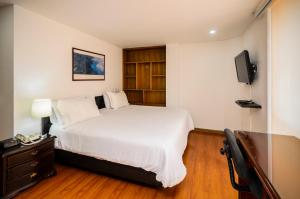 a bedroom with a white bed and a tv at Travelers Fontana Plaza in Bogotá