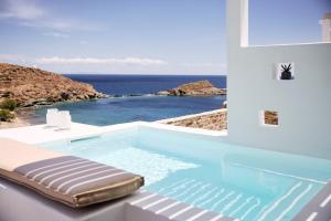 a swimming pool with a chaise lounge next to the ocean at Wise Luxury Suites in Kithnos