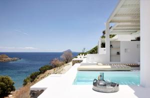 a white house with a swimming pool overlooking the ocean at Wise Luxury Suites in Kithnos