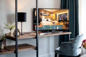 a room with a television on a desk with a bed at Boutique Hotel First City in The Hague