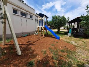a playground with a blue slide in a yard at Kamp Rujno in Starigrad