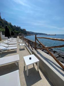 uma fila de mesas e cadeiras brancas junto ao oceano em Hotel Lorelei Londres em Sorrento