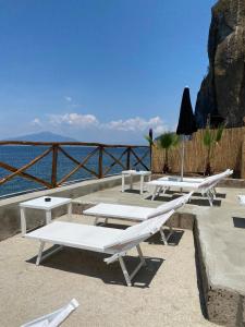 un gruppo di tavoli da picnic con l'oceano sullo sfondo di Hotel Lorelei Londres a Sorrento