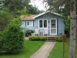 una casa azul con dos sillas blancas en el patio en Chalets Laurentides Mont-Tremblant, en Mont-Tremblant