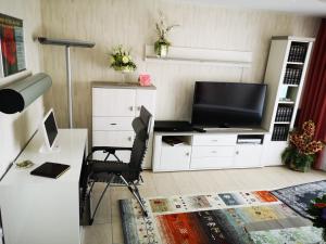 a living room with a tv and a desk with a chair at Grünheide am See in Alt Buchhorst