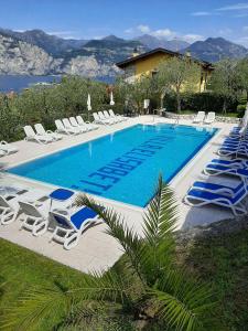 une grande piscine avec des chaises longues dans l'établissement Appartamenti Elisabeth, à Brenzone