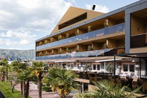 a building with palm trees in front of it at Weinegg Wellviva Resort in Appiano sulla Strada del Vino