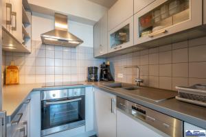 kuchnia z białymi szafkami, zlewem i kuchenką w obiekcie Valentino 0401 w mieście Koksijde