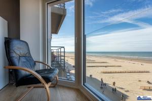 a chair in a room with a view of a beach at Valentino 0401 in Koksijde