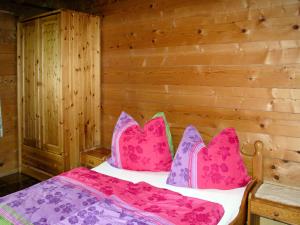 Schlafzimmer mit einem Bett mit rosa und lila Kissen in der Unterkunft Apartment Geislhof - BMG195 by Interhome in Bramberg am Wildkogel