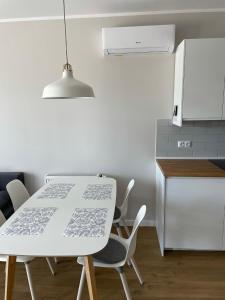 uma cozinha com uma mesa e cadeiras brancas e um frigorífico em Gąski Apartament Nadmorski em Gąski