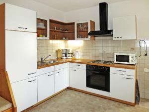 eine Küche mit weißen Schränken und einem Herd mit Backofen in der Unterkunft Apartment Kohler - FGZ121 by Interhome in Fügen