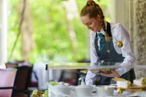 una mujer sosteniendo una bandeja de comida en una mesa en Hotel Meudon, en Falmouth