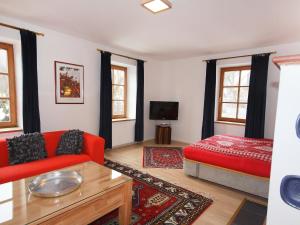 ein Wohnzimmer mit einem roten Sofa und einem Bett in der Unterkunft Chalet Ferienhaus Dr-Steiner by Interhome in Zell am See