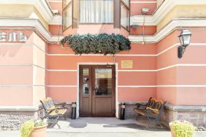 a pink building with two chairs and a door at Palantin Hotel in Saint Petersburg
