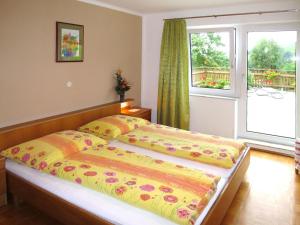 1 dormitorio con 1 cama con edredón amarillo y ventana en Holiday Home Mayrhofer - MON240 by Interhome en Oberwang