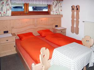 sypialnia z 2 łóżkami z pomarańczową pościelą i stołem w obiekcie Apartment Barbara - ZAZ614 by Interhome w mieście Aschau