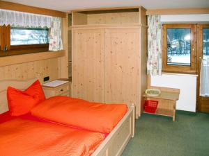 sypialnia z pomarańczowym łóżkiem i szafką w obiekcie Apartment Barbara - ZAZ614 by Interhome w mieście Aschau