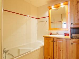 een badkamer met een bad, een wastafel, een bad en een spiegel bij Apartment Les Origanes-7 by Interhome in Les Menuires