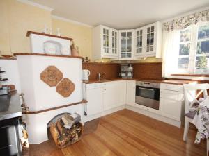 eine Küche mit weißen Schränken und Holzböden in der Unterkunft Villa Marie-Sophie by Interhome in Mallnitz