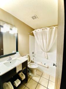 a bathroom with a sink and a toilet and a tub at Super 8 Grand Rapids City Center in Wyoming
