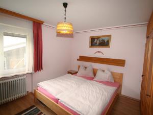 a bedroom with a bed and a window and a chandelier at Apartment Haus Viktoria by Interhome in Fürstau