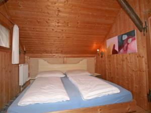 a bed in a wooden cabin with two pillows at Chalet Troadkasten by Interhome in Neuhofen im Innkreis