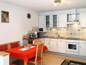 cocina y comedor con mesa roja y sillas en Apartment Bergkristall - SIX115 by Interhome, en Spiss